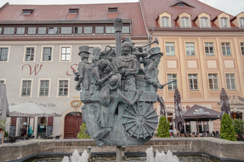 Charming bronze sculpture in a European town square with historic architecture.
